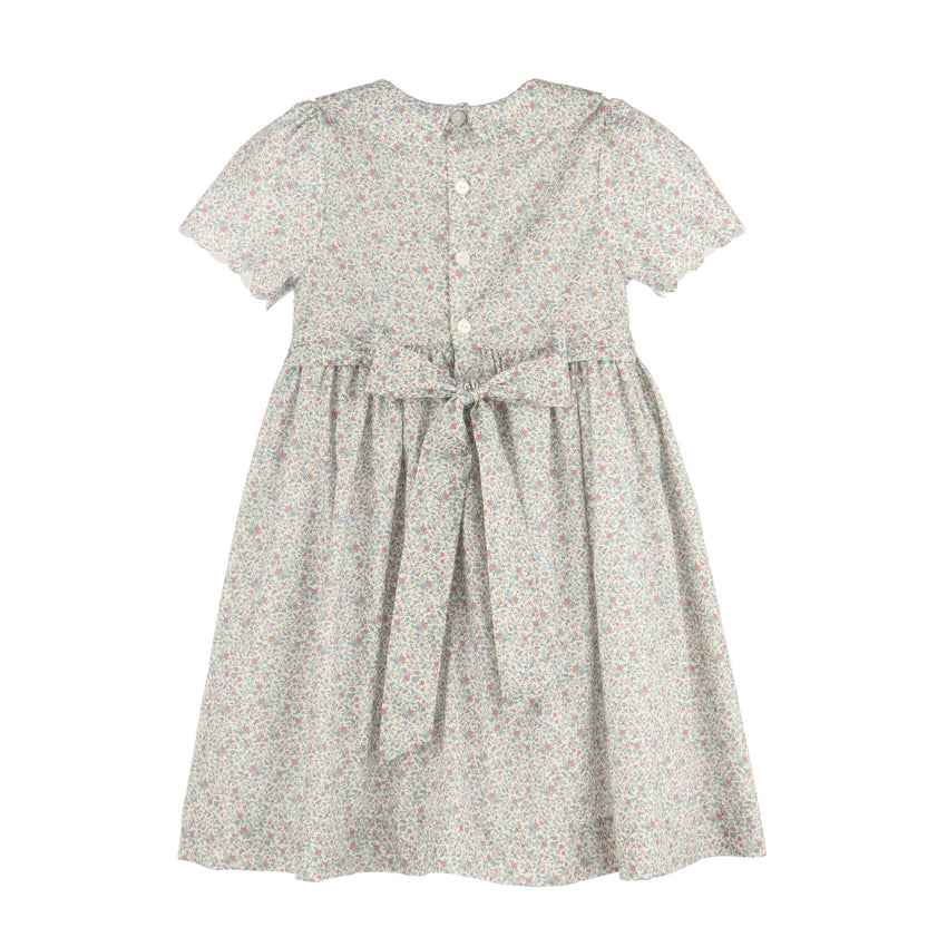 A short-sleeve dress with a small-scale floral print in muted green, pink, and beige tones on a white base. It features a buttoned back, a gathered waist, and a matching fabric tie belt, shown against a plain white background.