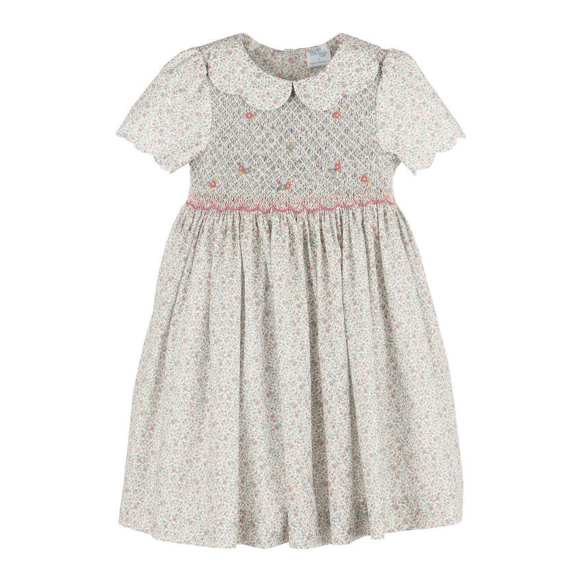 A girl's short-sleeve dress with a white and pink floral print, featuring a smocked bodice with small embroidered flowers and a Peter Pan collar.