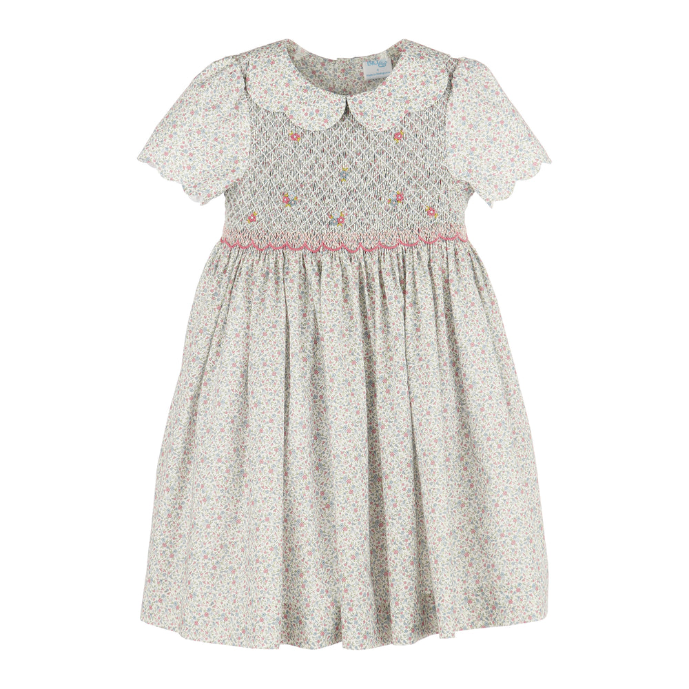 A girl's short-sleeve dress with a white and pink floral print, featuring a smocked bodice with small embroidered flowers and a Peter Pan collar.