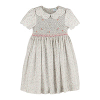 A girl's short-sleeve dress with a white and pink floral print, featuring a smocked bodice with small embroidered flowers and a Peter Pan collar.