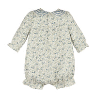 A baby romper with a dense blue and green floral print on a cream background, featuring a Peter Pan collar with blue trim, buttoned back, and ruffled cuffs and leg hems.