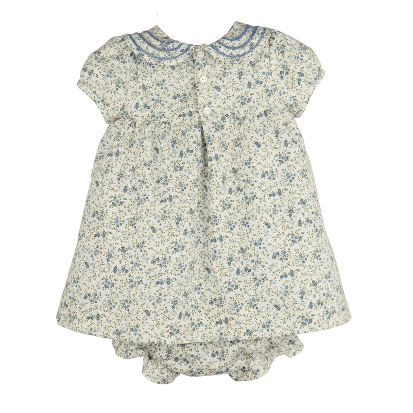 A girl's short-sleeve dress with a blue and green floral print on a cream background, featuring a Peter Pan collar with blue trim and a ruffled hem.