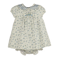 A girl's short-sleeve dress and matching bloomers set in a cream-colored fabric with a blue and green floral print. The dress features a Peter Pan collar with blue embroidered trim and a small blue bow at the center chest.