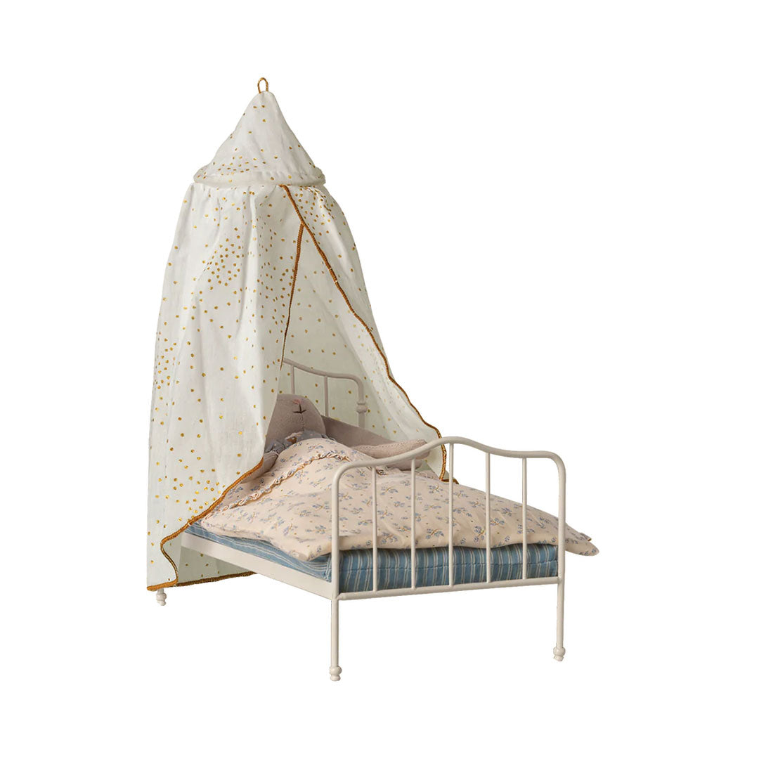 A white metal toddler bed with a matching canopy net featuring gold star patterns and gold trim, styled with a patterned quilt and pillow on a white background.