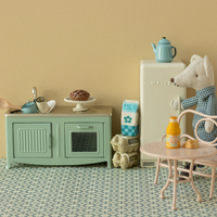 Mouse in its kitchen with table, refrigerator, sink, oven, eggs, coffee pot and a small table and chair.