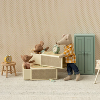Toy mice in their matchbox beds, a dad mouse overseeing them  Clocks and dresser in room against a beige wall.