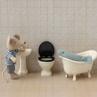 Miniature bathroom set with a mouse character, toilet, and bathtub against a patterned wall.