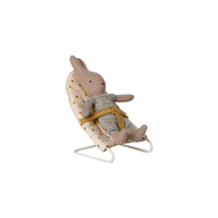 Baby toy mouse strapped in polka dot baby bouncer on a white background.