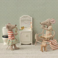 Miniature bathroom scene with toy mice and bathroom furniture against a patterned wall.