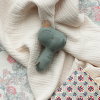 Green rhino rattle on a pile of blankets.