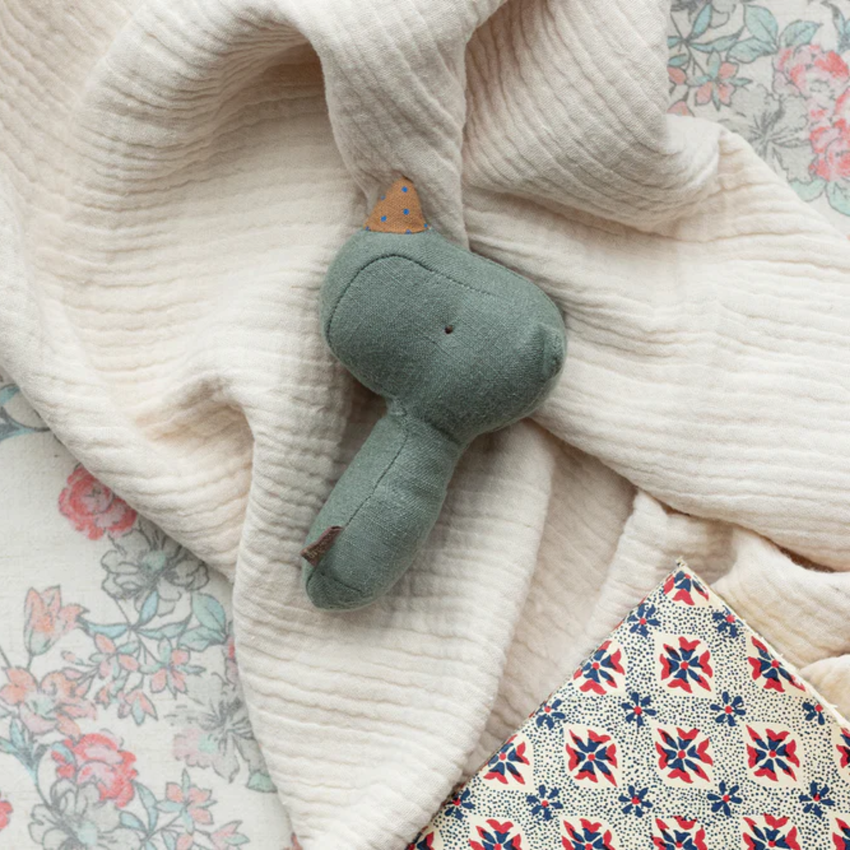 Green rhino rattle on a pile of blankets.