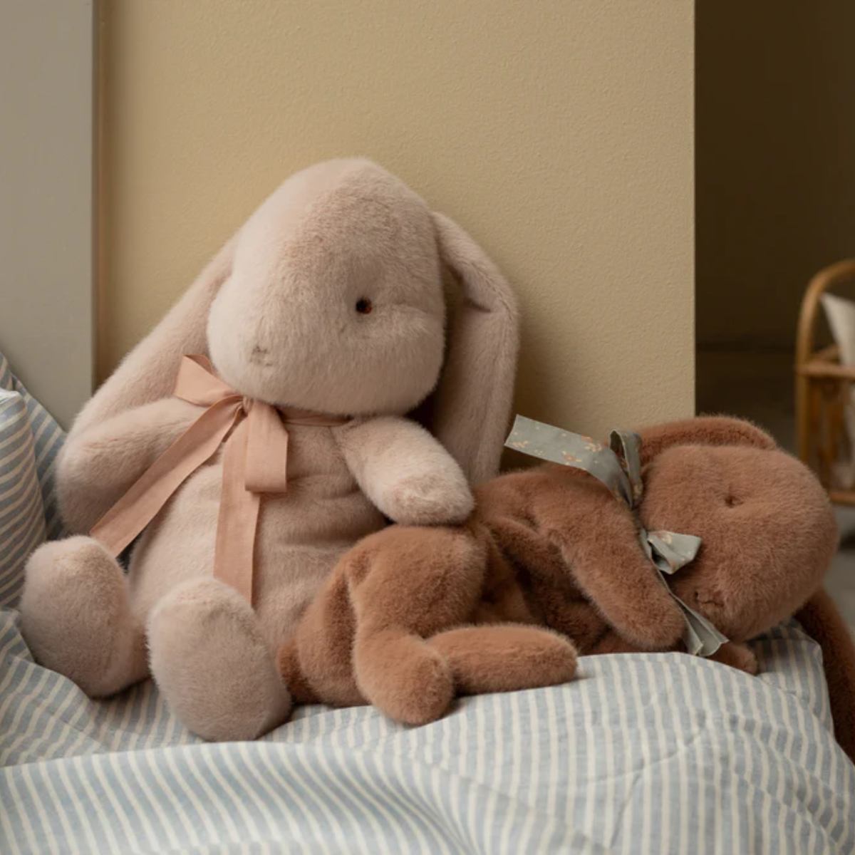 Two plush rabbits toy sitting on a striped surface.