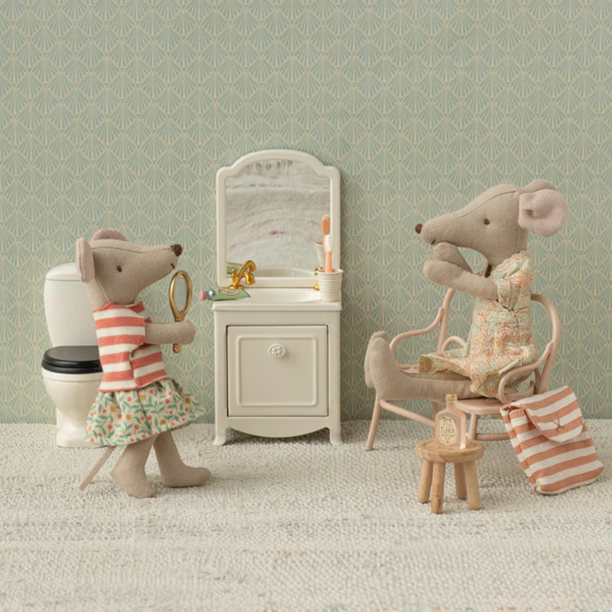 Two toy mice in a bathroom setting with a sink, mirror, and toilet.