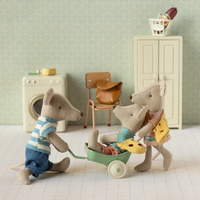 Three toy mice in a room setting with a washing machine, chair, and cabinet.  Two mice playing with smaller mouse in a pull toy.