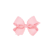 Pink bow with scalloped edges on a white background.