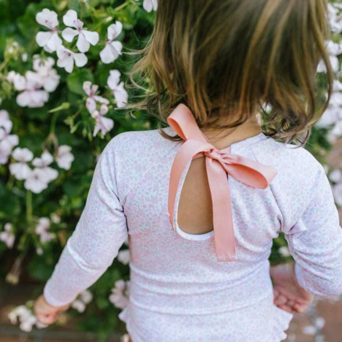 Pink floral long-sleeve swimsuit with back neck bow and ruffles at leg opening