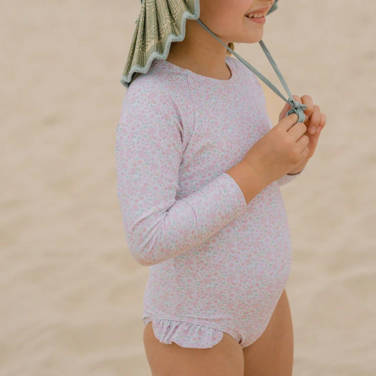 Pink floral swimsuit with long sleeves and ruffles along the leg opening