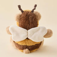 A plush toy shaped like a bee, shown from the back. It has a soft brown and yellow striped body, a large white wing on each side, and dark brown antennae, photographed against a plain beige background.