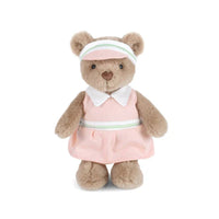 Teddy bear in a pink golf dress with a white collar and visor on a white background.