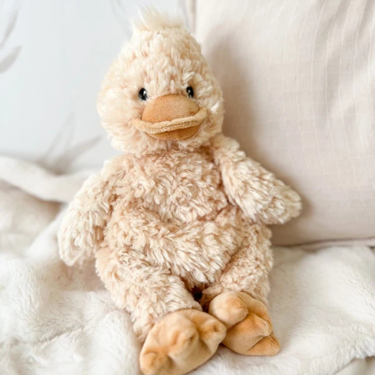 Plush duck toy on a soft white surface.