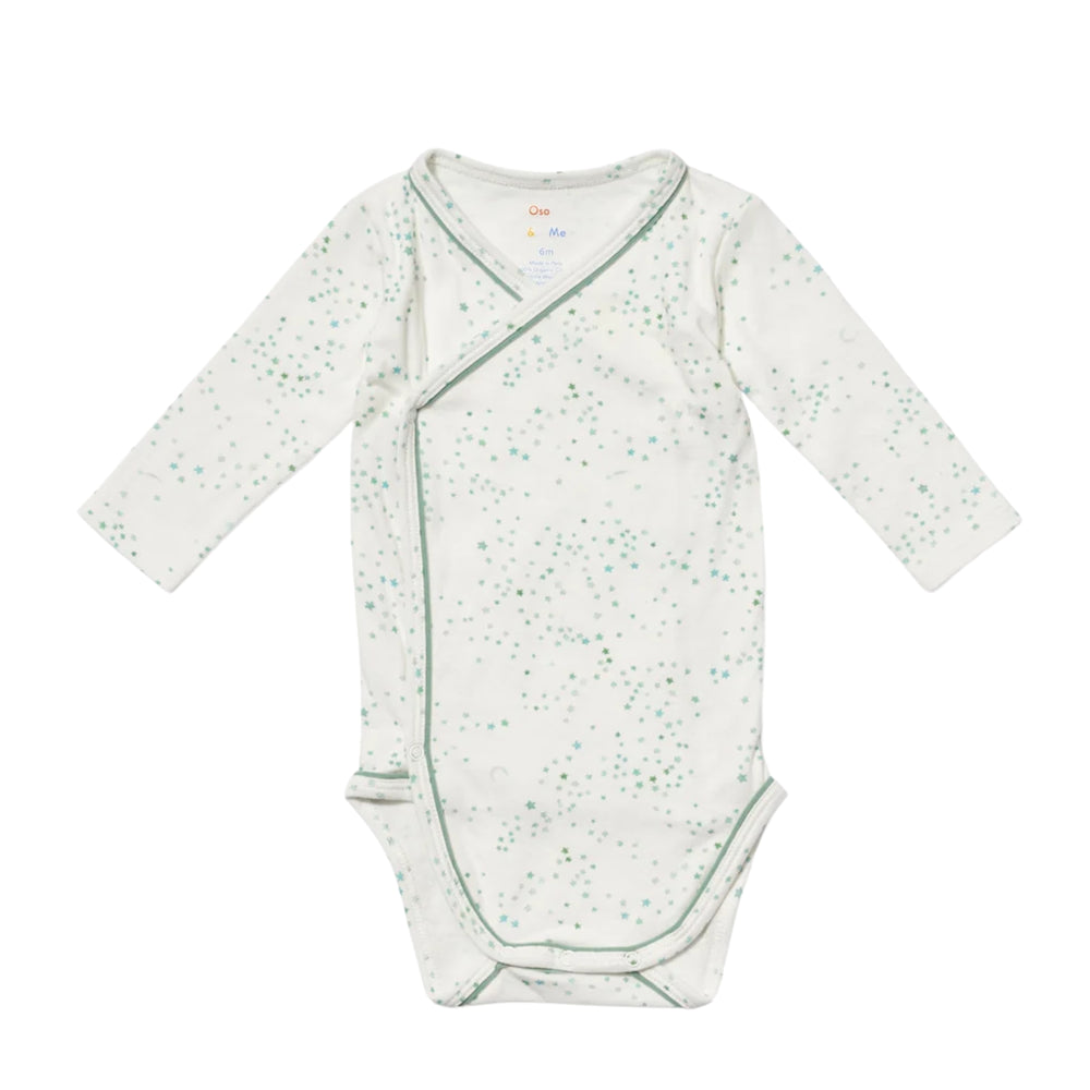 A long-sleeve baby crossbody wrap bodysuit in white with a light green speckled pattern and green piping, laid flat on a white background.