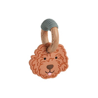 A baby teething toy featuring a sculpted golden doodle dog face in a warm terracotta-brown color, attached to a natural wood ring with a gray ribbed silicone loop at the top, shown on a plain white background.