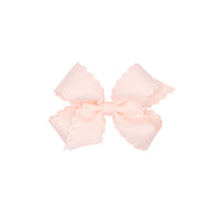 Rose pink colored bow with scalloped edges on a white background.
