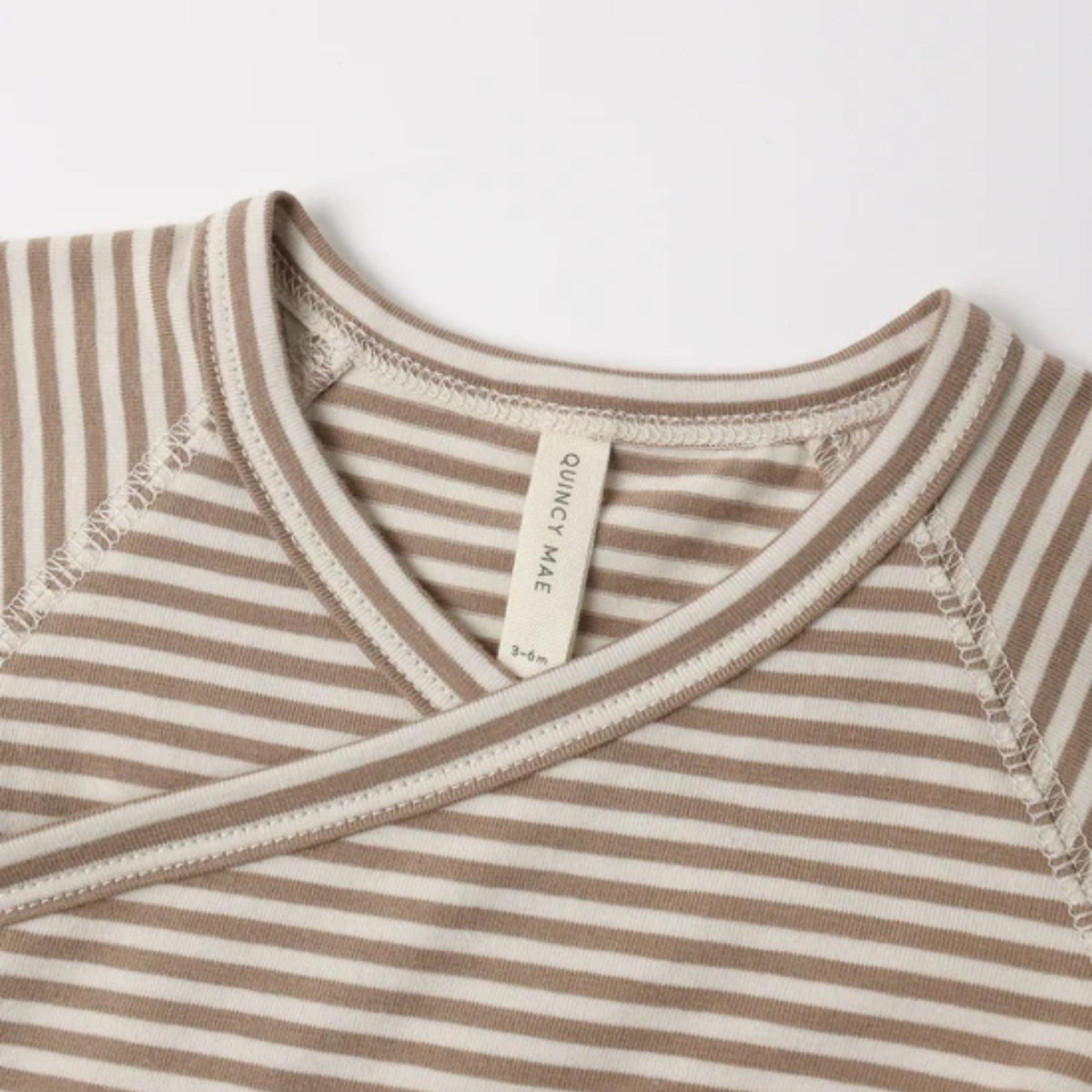 Close-up of a striped baby wrap top with a V-neck and crossover front on a white background.