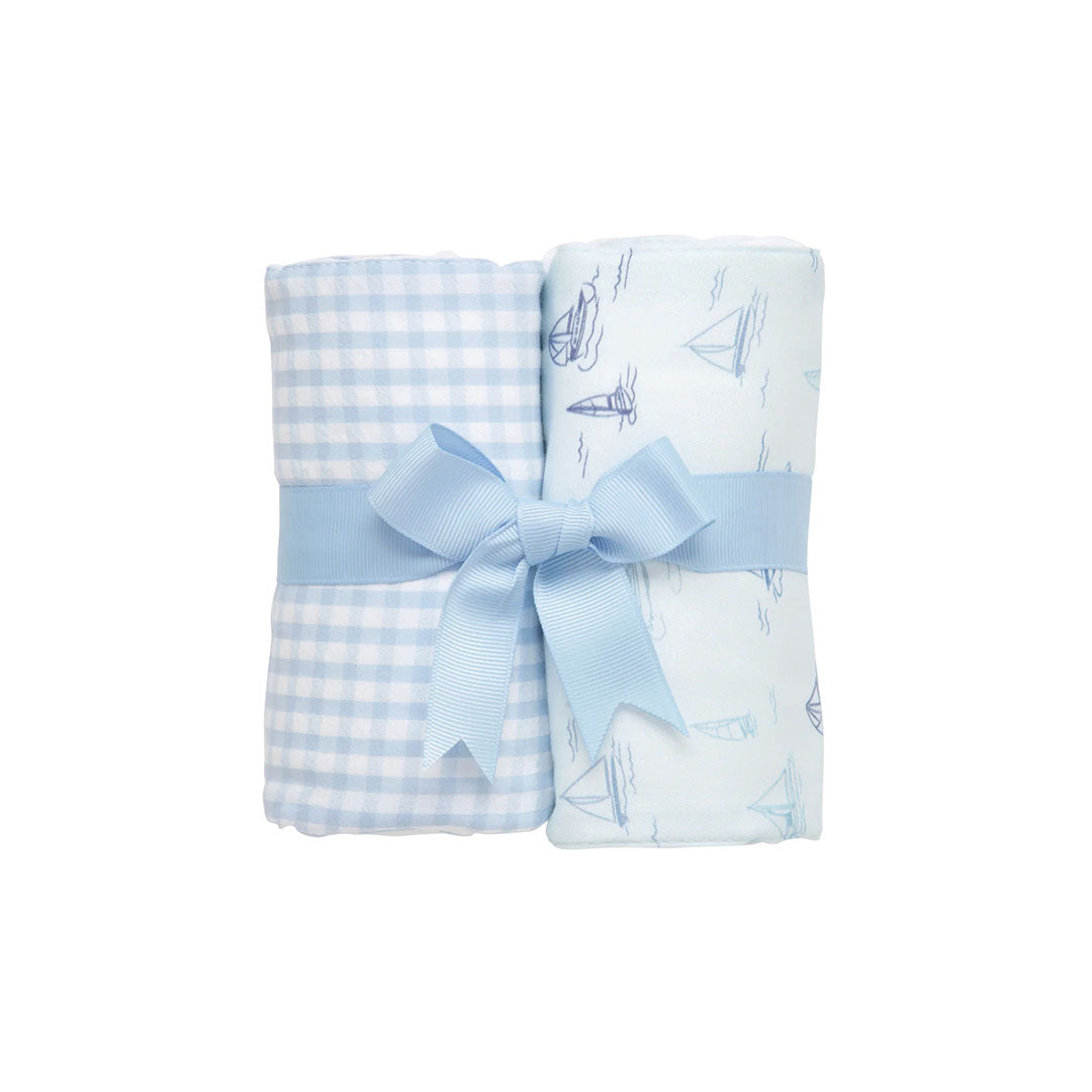 Two burp cloths - blue and white check and a sailboat design- a blue bow on a white background.