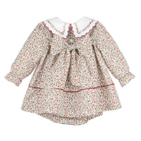 A long-sleeve dress with a dense red, green, and beige floral print, featuring a white Peter Pan collar with red trim, a central bow, and a tiered ruffled hem.