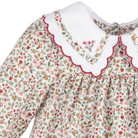 A close-up of a long-sleeve dress featuring a delicate red, pink, and green floral print on an off-white background, with a contrasting white Peter Pan collar trimmed in red and white.
