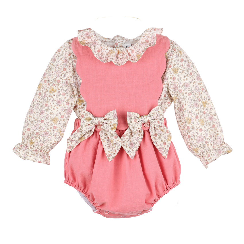 Pink baby romper with floral long-sleeve top and bows on the front on a white background.