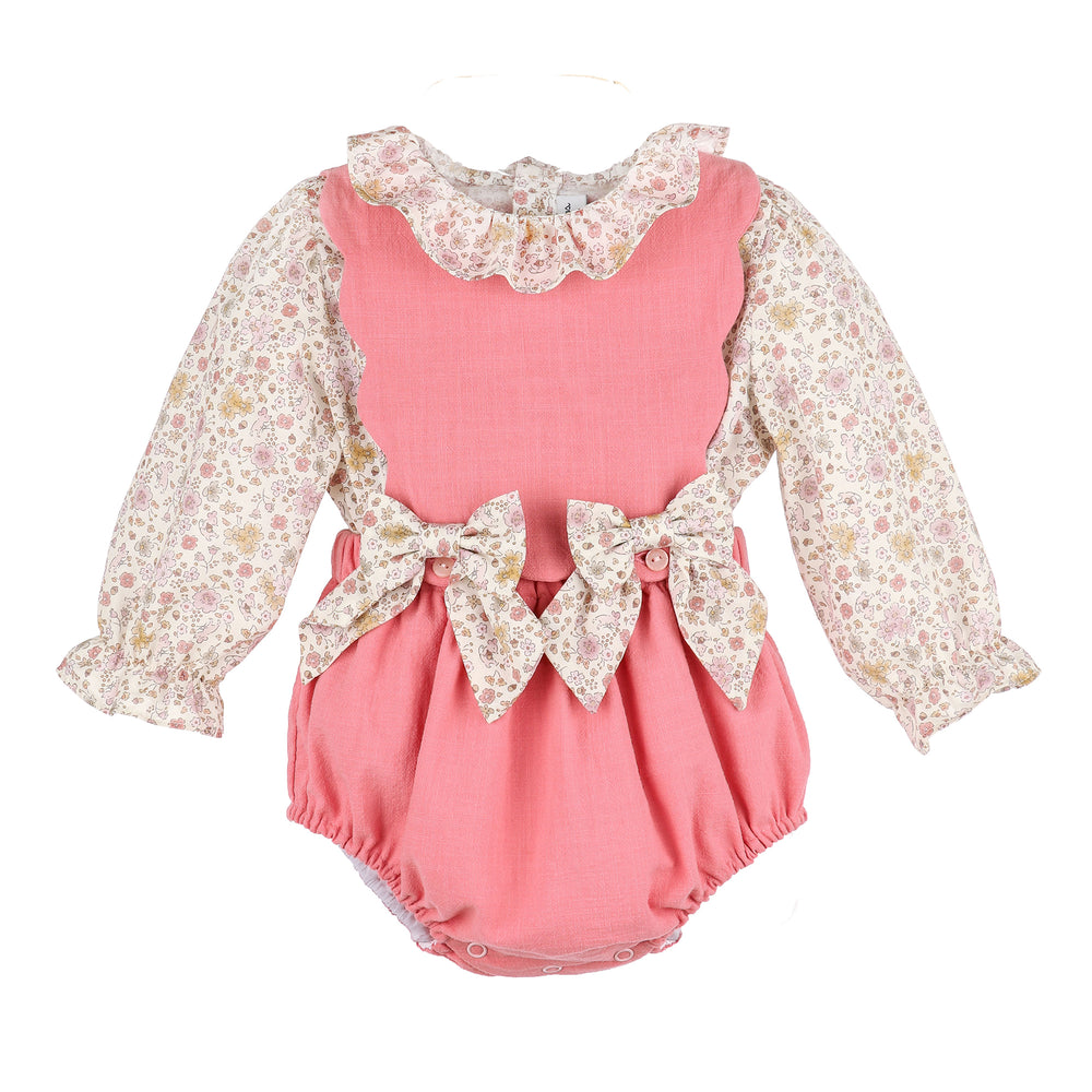 Pink baby romper with floral long-sleeve top and bows on the front on a white background.