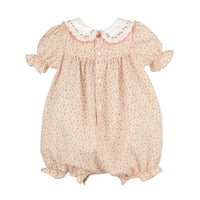 A girl's short-sleeve romper in a light peach-pink floral print, featuring a white Peter Pan collar with embroidered green leaves and a pink border, and a button-up back.