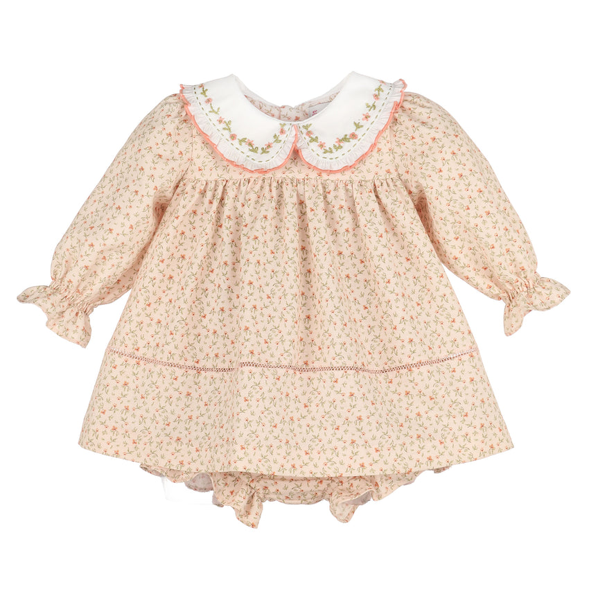 A girl's long-sleeve dress in a light peach and pink floral print, featuring a white Peter Pan collar with pink embroidered trim and ruffled cuffs.
