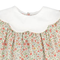 Close-up of a children's dress with a white Peter Pan collar and a cream floral print bodice featuring red, pink, and green flowers.