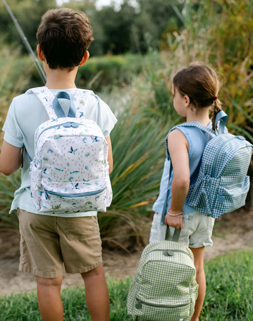 Two children with gingham and print backpacks standing outdoors 