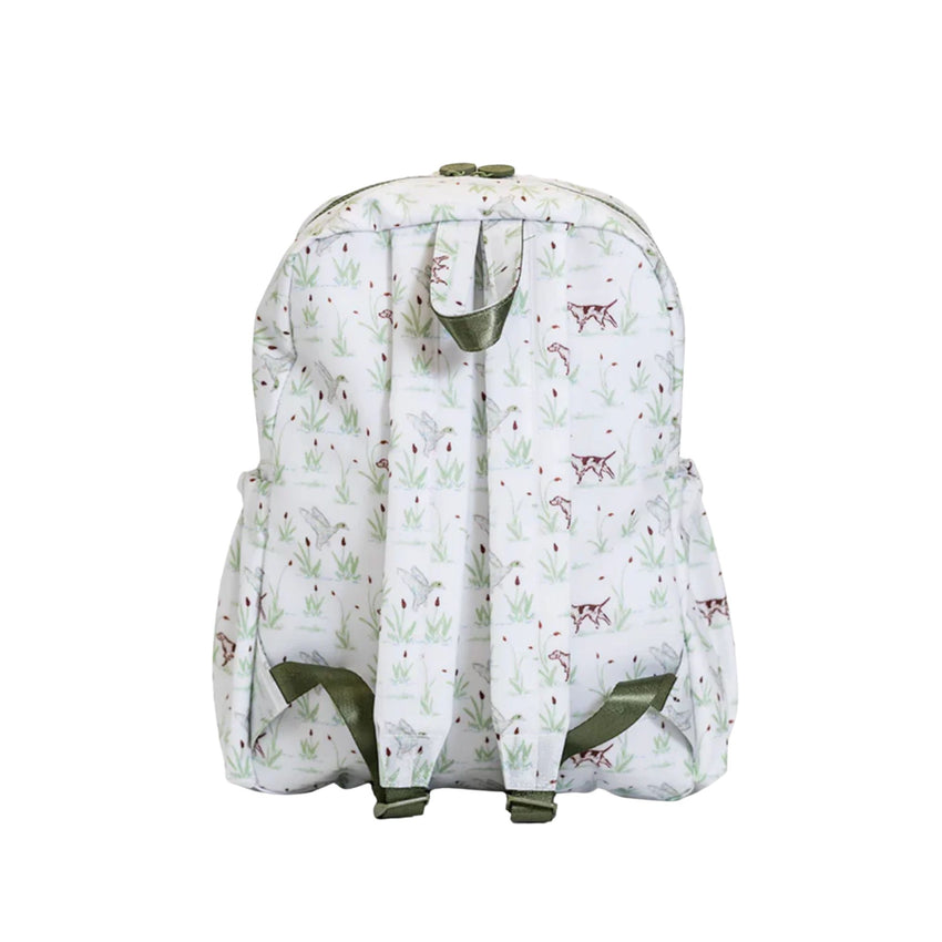 A white backpack featuring an all-over print of small brown dogs and green reeds, with olive green straps and trim, shown against a plain white background.
