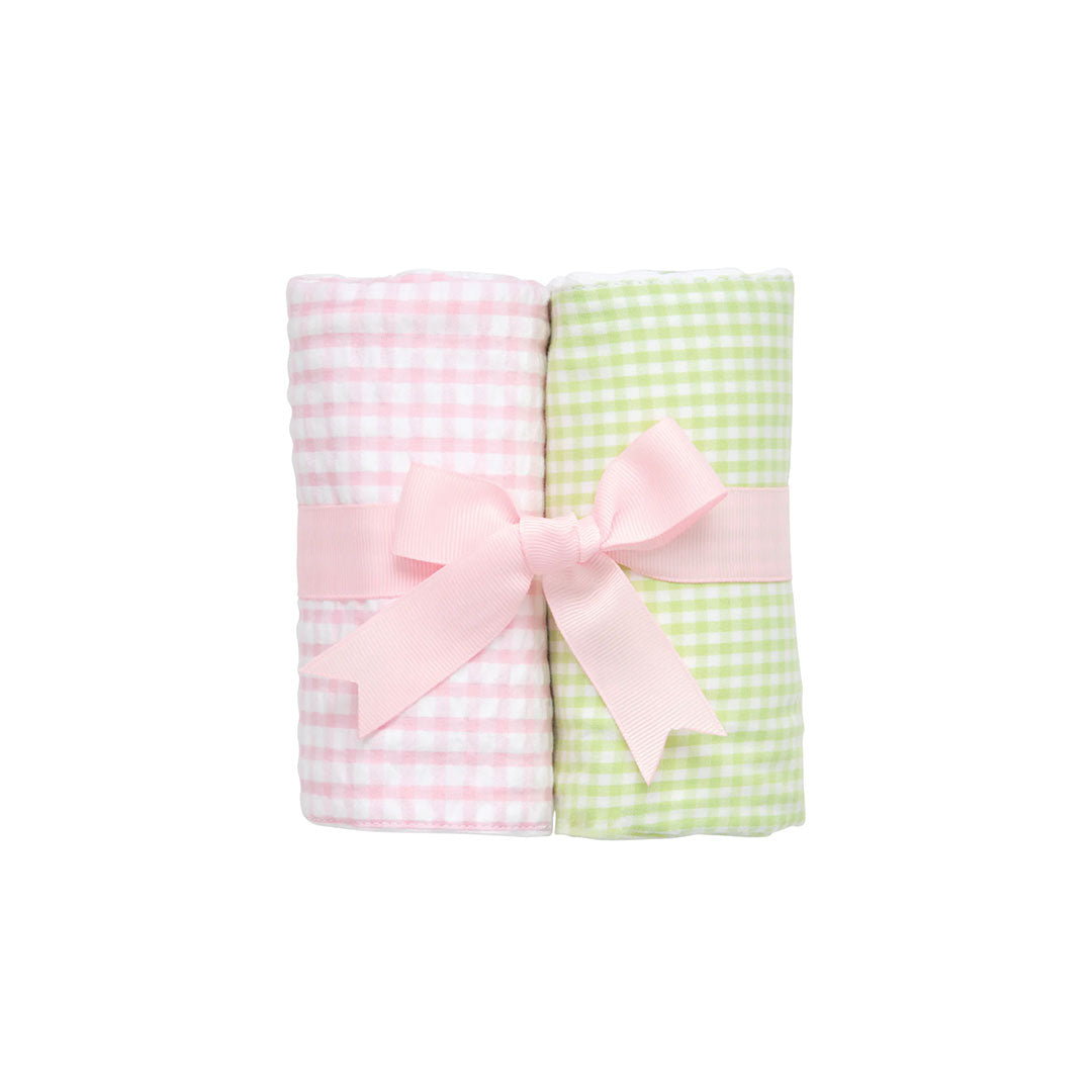 Two rolled checkered burp cloths - green and white check and pink and white check - with a pink bow on a white background.