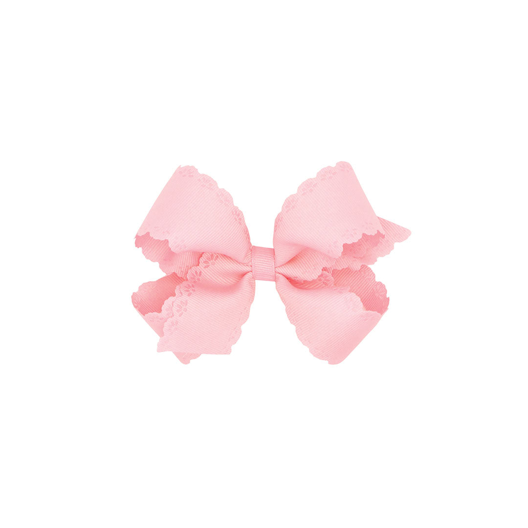 Pink bow with scalloped edges on a white background.