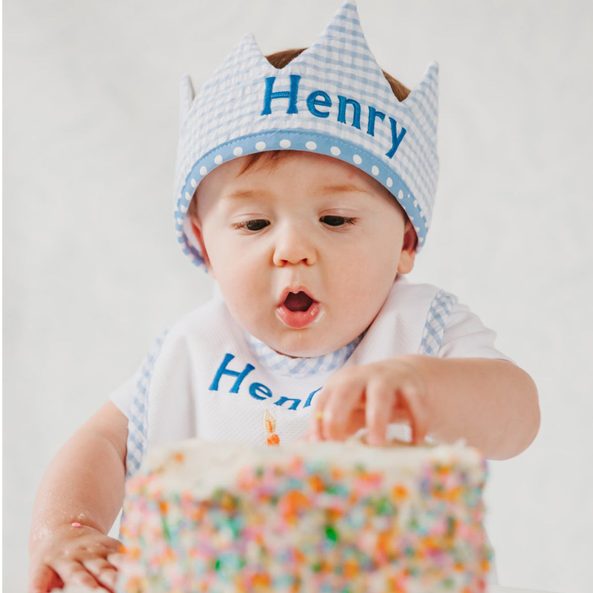 Blue birthday crown on model with embroidered name on bib and crown.